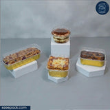 Four different baked goods in clear plastic clamshell and rectangular containers, displayed on white geometric risers against a gray studio background. An ezeepack.