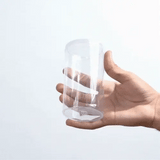 Clear plastic cup held in a hand against a white background