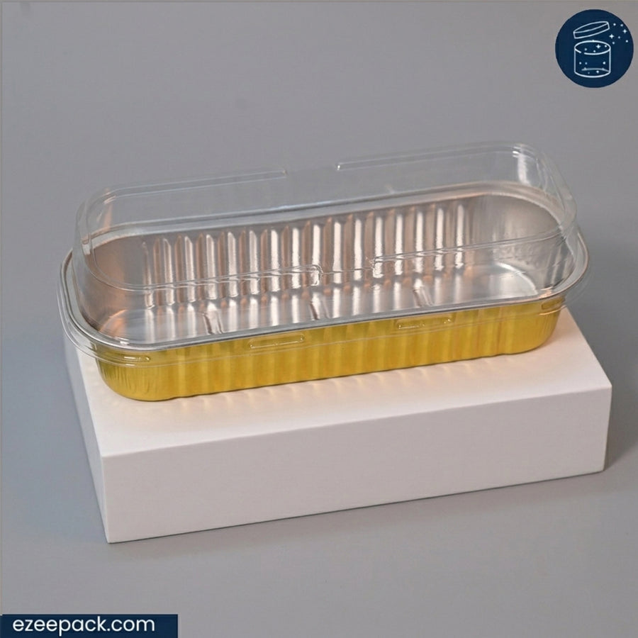 A clear plastic clamshell lid layered over a gold foil tray, displayed on a white rectangular block against a gray background.