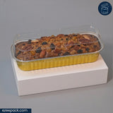 A rectangular loaf of fruit and nut bread in a clear plastic clamshell container with a yellow base, displayed on a white pedestal against a gray background.